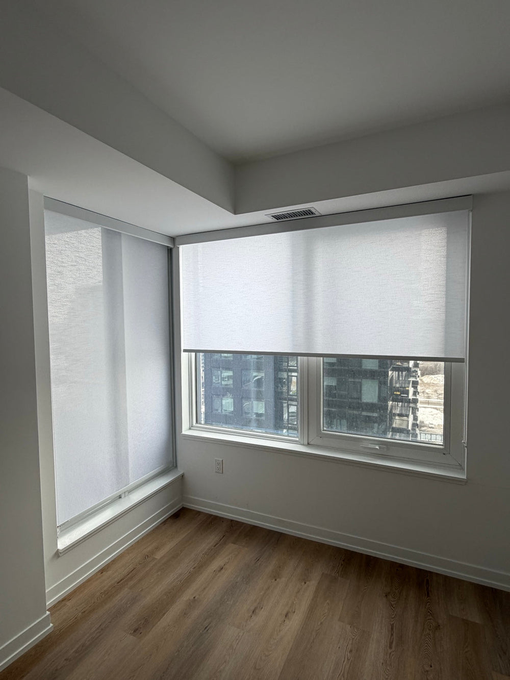 White roller shades across kitchen and living-area windows.